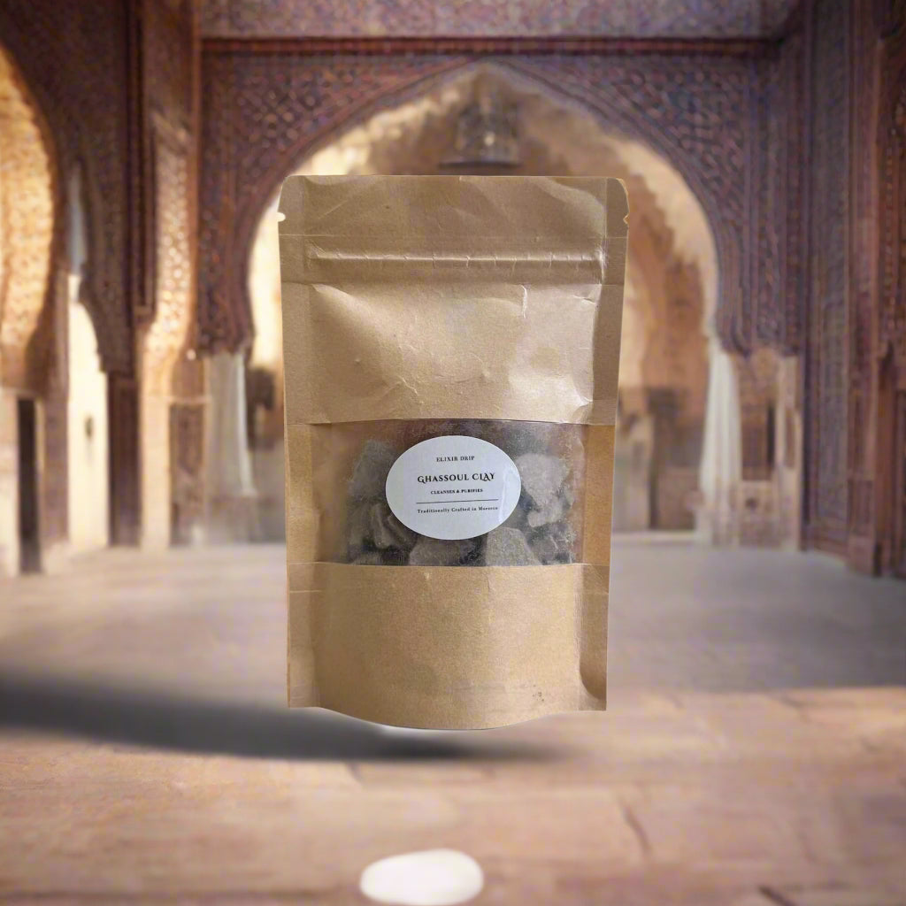 A pouch of Pure Moroccan Ghassoul Clay displayed against an indoor backdrop with arches, likely representing a traditional Moroccan setting.