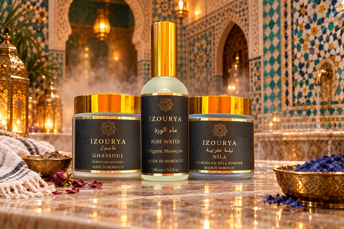 Three cosmetic products from the brand IZOURYA are arranged against a plain white background: a central bottle of Rose Water with a gold cap, flanked by two jars labeled Ghassoul and Mila with gold and orange-gold lids.