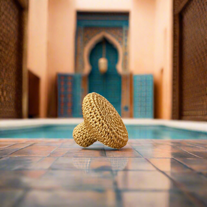 A Moroccan face exfoliating tool with a textured, beige surface, isolated on a black background.