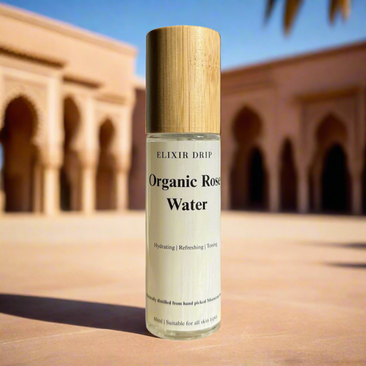 A clear glass bottle with a wooden cap labeled as 'Organic Rose Water' by Elixir Drip.